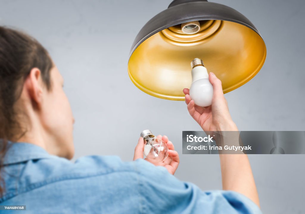 woman changing old incandescent light bulb to led energy saving lamp
